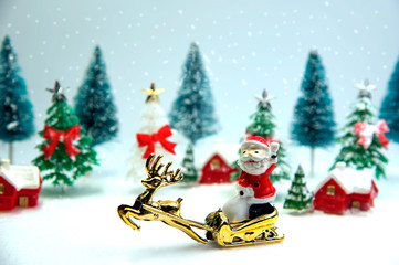 Green and white christmas tree with Santa and raindeer with snow. They are toy.