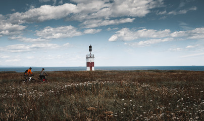 A girl and a lonely red-white lighthouse in an autumn field on the shores of the Okhotsk Sea in the north of the Khabarovsk Territory of Russia