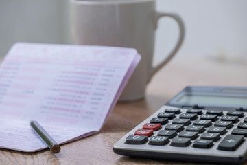 calculator,pencil , bankbook ,coffee cup  Put on a wooden table.