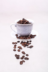 The white cup is filled with coffee beans