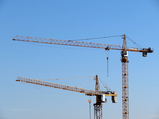 Yellow construction cranes isolated on clear blue sky background