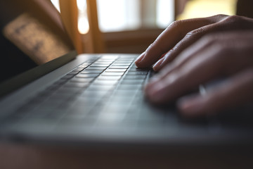 Closeup image of hands using and typing on laptop keyboard on wooden table