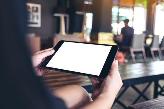 Mockup image of woman's hands holding black tablet pc with white blank desktop screen in cafe