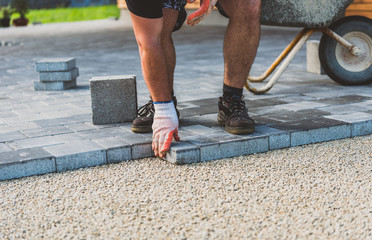 Laying gray concrete paving slabs in house courtyard driveway patio.