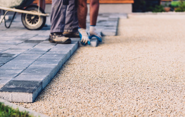 Laying gray concrete paving slabs in house courtyard driveway patio.