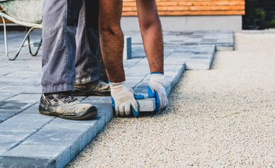 Laying gray concrete paving slabs in house courtyard driveway patio.
