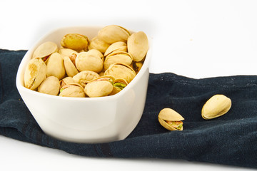 Pistachio in white bowl on black cloth