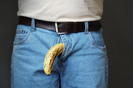 old limp drooping banana hanging from genital area of clothed unrecognizable man, impotence erectile dysfunction or limp-dick concept