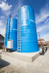 Obraz premium Blue water tower with a white staircase and a black hose