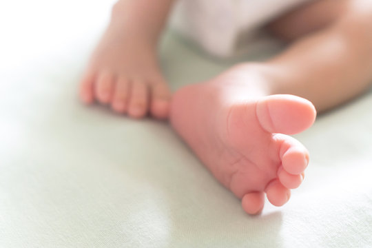 little tiny feet and toes of happy newborn baby sleeping in the baby bed in the morning sunlight. family and healthy baby concept. selective focus and soft tone photo.