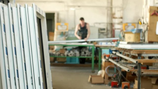 The production of assembly and manufacturing of PVC windows, a workshop with finished products, in the background, a worker measures the PVC profile for further assembly of the PVC window, processing