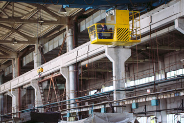 Fototapeta premium The girl working in the cab of a crane. Heavy industry, metal factory.