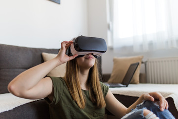 Beautiful young woman enjoying virtual reality at her home.