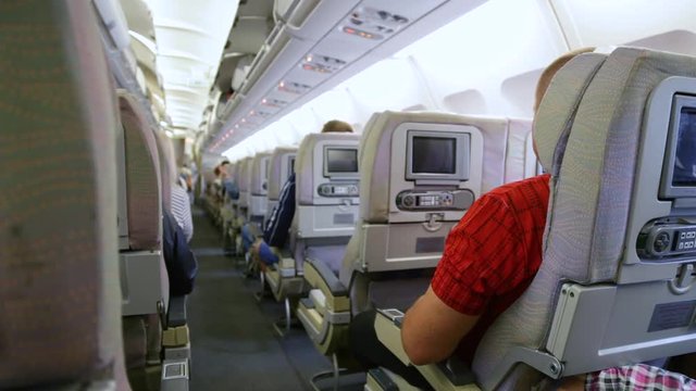 Interior of airplane with anonymous passengers sitting on their seats while waiting of take off. Real time full hd video footage.