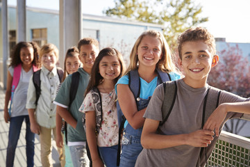 Elementary school kids with backpacks smiling to the camera