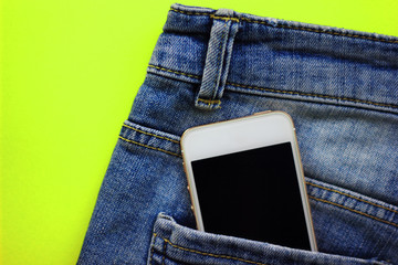 smartphone in a pocket of blue jeans on a colored background, space for text, concept