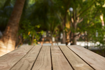 Empty top of natural wooden table for product placement and display in open shade. Coconut palm trees and green tropical plants on background. Maldives