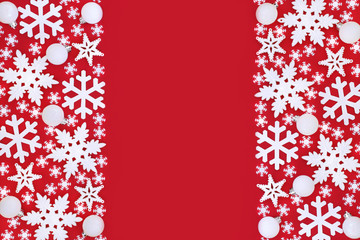 Snowflake and ball bauble decorations forming an abstract background border on red with copy space.