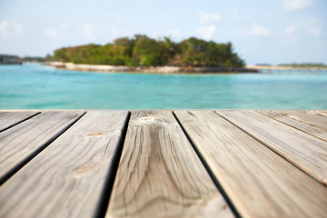 Fototapeta premium Empty white wood surface over blur blue ocean lagoon and sky and tropical for product placement and display.