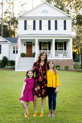 Mom and Two Daughters Hugging Outside their New Farmhouse Home