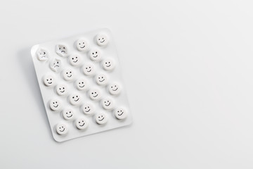 Blister with painted smileys on a white background.