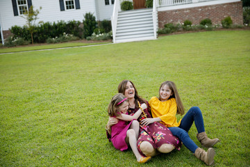 Mom and Two Daughters Laying on Ground Grass Wrestling Being Silly Having Fun Laughing