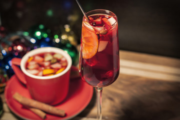 Бокал и чашка с глинтвейном на деревянном фоне с новогодними огнями 