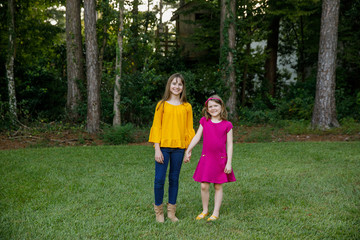 Obraz premium Beautiful Sisters in Their Backyard Holding Hands