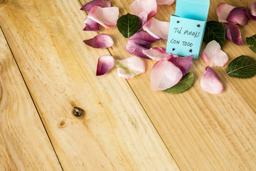 Flower petals on light wooden background with motivating phrase