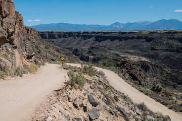 Dangerous dirt road at the canyon rim of the Rio Grande Gorge near Taos, New Mexico with the Sangre de Cristo mountain range in the background