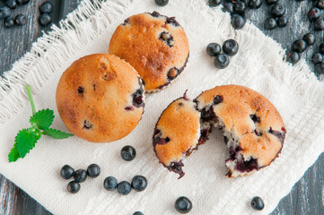 Blueberry muffins which are decorated with blueberries and mint. Photo in a rustic style on a wooden background. Blurred.