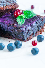Delicate chocolate brownies with blueberries. Decorated with a sprig of mint and berries. Isolated over white background.
