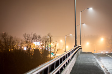 A road and rail in the fog in a city at night.