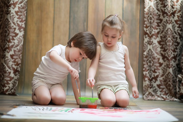 Naklejka premium Little children paint on a large sheet of paper