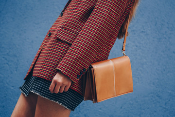 street style, attractive woman wearing a  mini skirt, check plaid blazer and a lether brown tote bag. fashion outfit perfect for autumn. style of 2018 autumn.