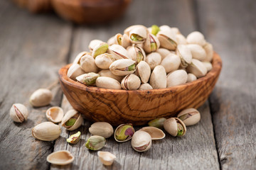 Bowl with pistachios on a wooden table. - Powered by Adobe