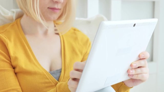 Portrait of attractive blonde Caucasian woman smiling and using digital tablet.