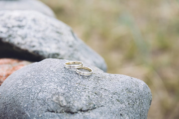 Pair of wedding rings sitting on a wall of granite rocks.