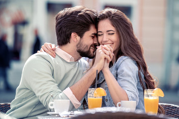 Couple in love in cafe laughing and hugging