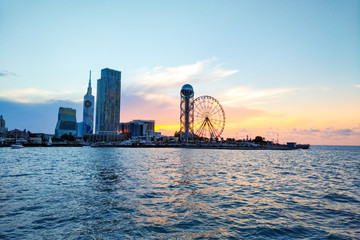 Panorama of Illuminated Resort city Batumi. Bright Evening Sky. View From Sea Beach To Illuminated Cityscape