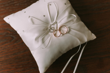Two Wedding rings on a small white pillow.