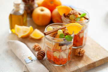 Concept of vitamin healthy salad with carrot, apples, orange, mixed nuts garnished with olive oil and cinnamon. Take away diet snack