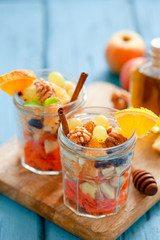 Concept of vitamin healthy salad with carrot, apples, orange, mixed nuts garnished with olive oil and cinnamon. Take away diet snack