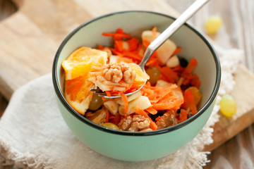 Concept of vitamin healthy salad with carrot, apples, orange, mixed nuts garnished with olive oil and cinnamon