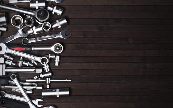 many adjustable and wrench spanners on a black wooden background