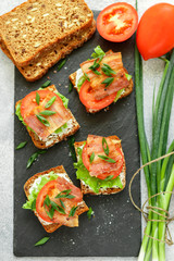 Mini toast of grain bread with tomatoes, bacon, lettuce and green onions