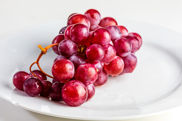 Beautiful close-up of cluster of red grapes (inks) on table. Fresh, raw and water drops.