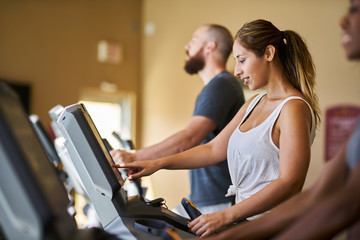 Fototapeta na wymiar three people using treadmills in gym together