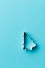 Christmas tree cookie cutter on blue background with copy space. Top view. Flat lay. Trendy...