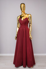 Fototapeta na wymiar Burgundy dress on gold mannequin